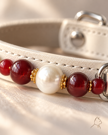 Close-up of shell pearl, red agate, and ivory stitching